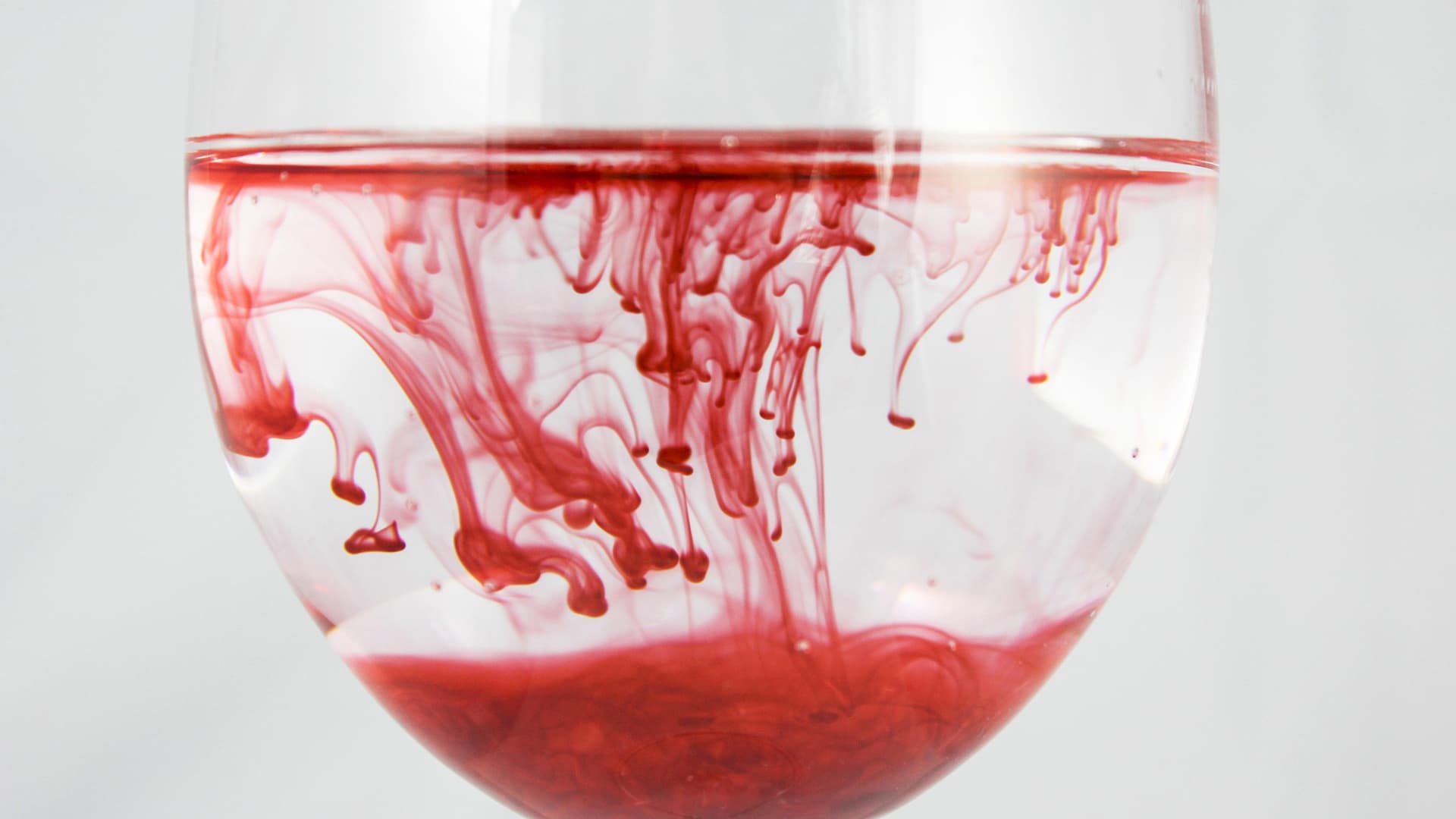 Rote Farbe verteilt sich in Wasserglas